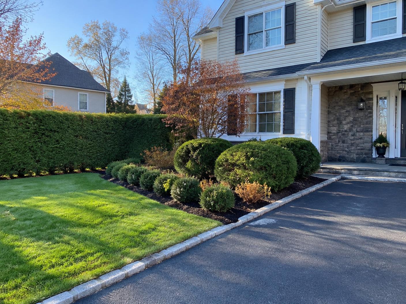 Trimmed hedges and mulched shrub beds along a driveway in Bergen County